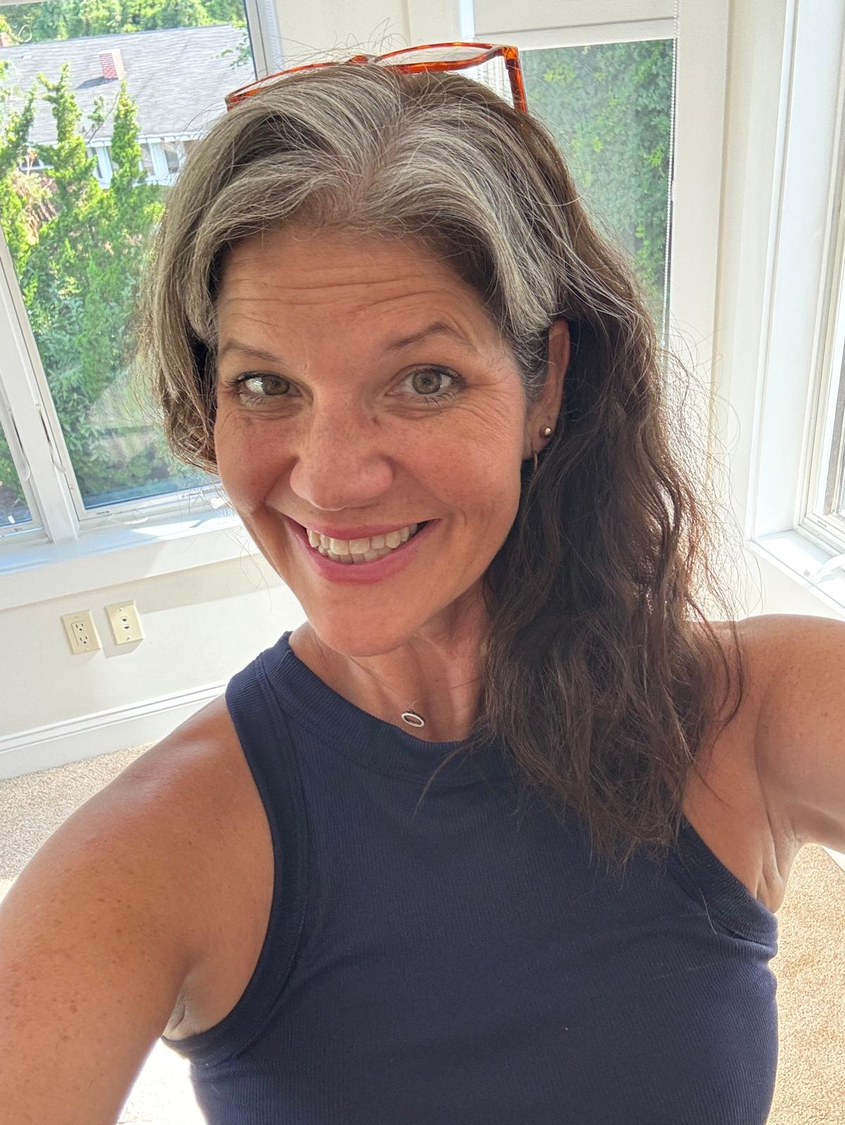 Tara smiling in a bright room by a window